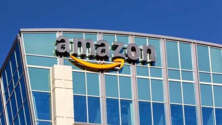 Amazon logo displayed on a glass office building against a clear blue sky?