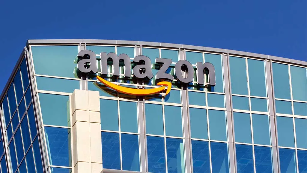 Amazon logo displayed on a glass office building against a clear blue sky?