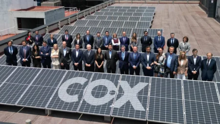 Group of professionals standing on a rooftop lined with solar panels, forming the letters COX in the foreground.