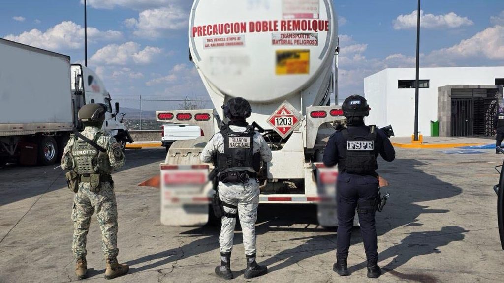 pipa guanajuato - Petróleo y Energía Three armed officers in tactical gear stand guard behind a large fuel tanker at a loading area, wearing vests labeled Ejército, Guardia Nacional, and FSPE on their backs.