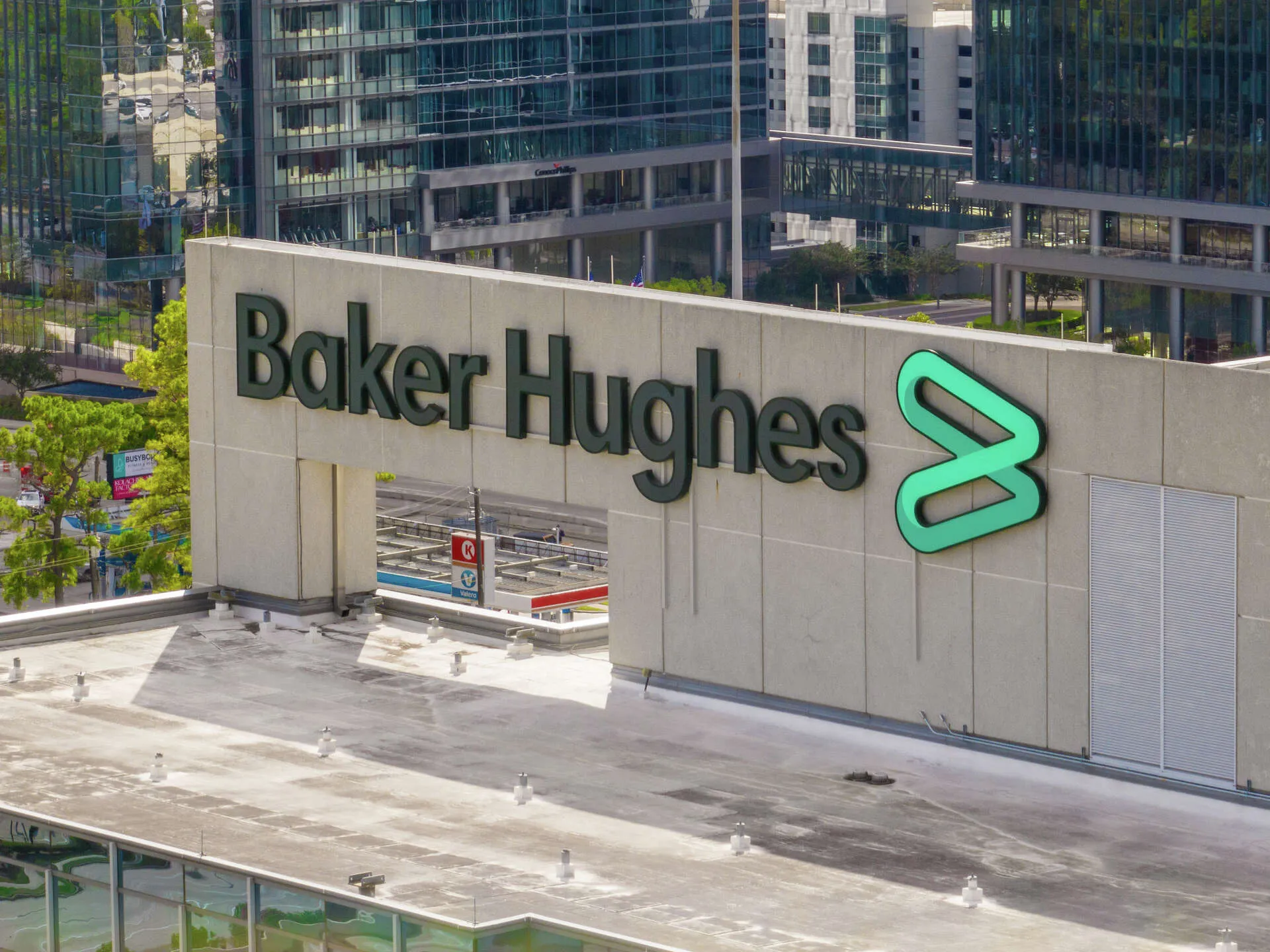 Baker Hughes sign on a modern office building with glass towers in the background.