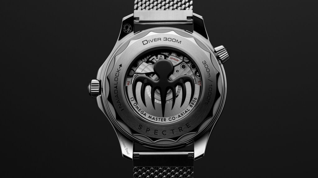 21030422001023_BondSpectre_ADV_SE_CaseBack_16_9_RVB - Petróleo y Energía Close-up of a stainless steel dive watch back, revealing the inner movement and rotor, with'DIVER 300M' and other engravings visible against a dark background.