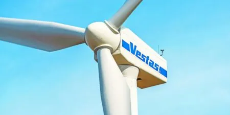 Wind turbine hub and blades with a Vestas logo against a clear blue sky.
