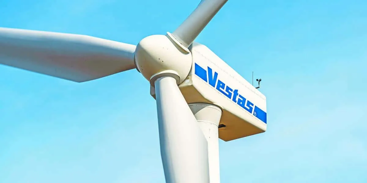 Wind turbine hub and blades with a Vestas logo against a clear blue sky.