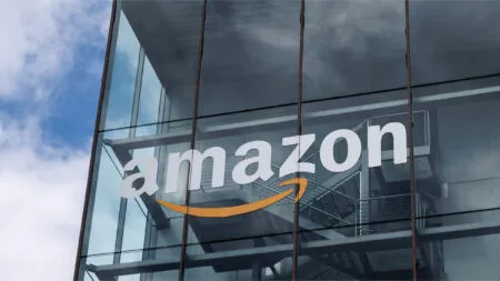 Close-up of a glass office building facade with the white Amazon logo and orange curved arrow at the bottom center.