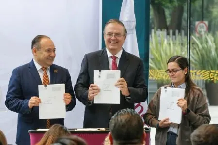 Three professionals in business attire hold signed documents and smile at a signing ceremony.