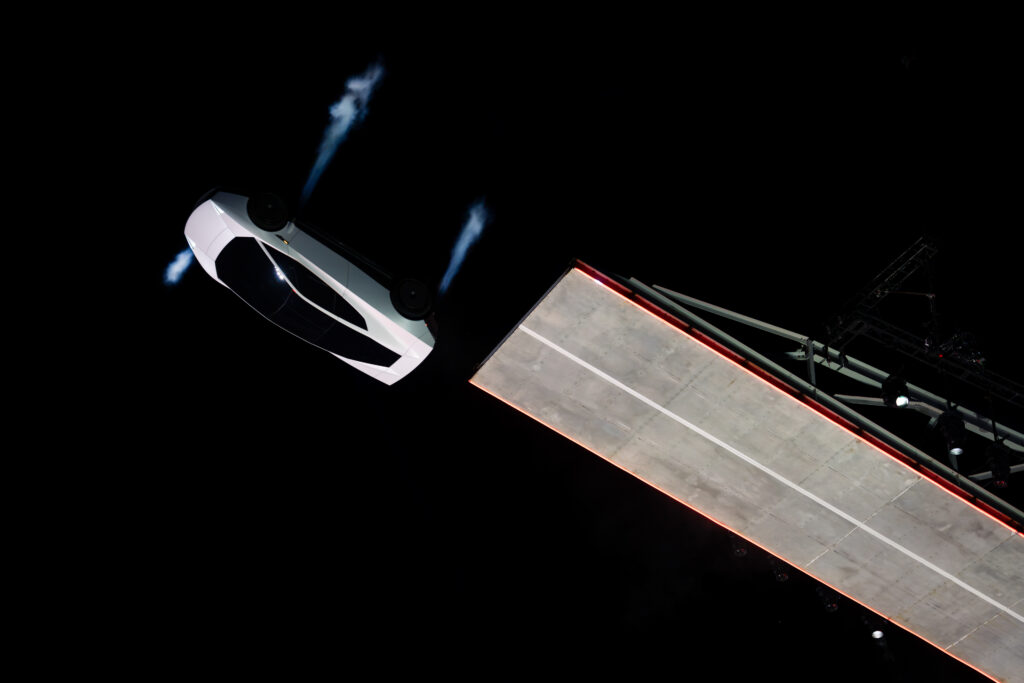 Roadster_56 - Petróleo y Energía White, angular spacecraft on a night launch pad with blue engine flames.