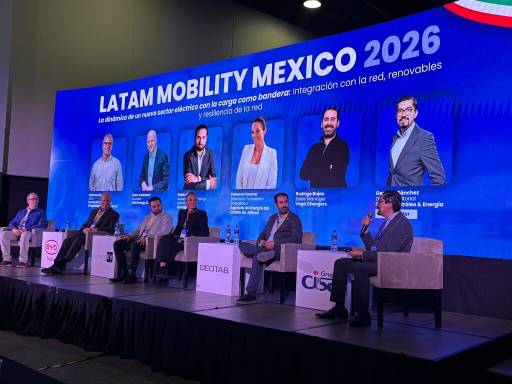 Panel "La nueva dinámica del sector eléctrico como bandera" - Petróleo y Energía Panel discussion on a blue stage backdrop reading LATAM MOBILITY MEXICO 2026, with seven speakers seated in armchairs.