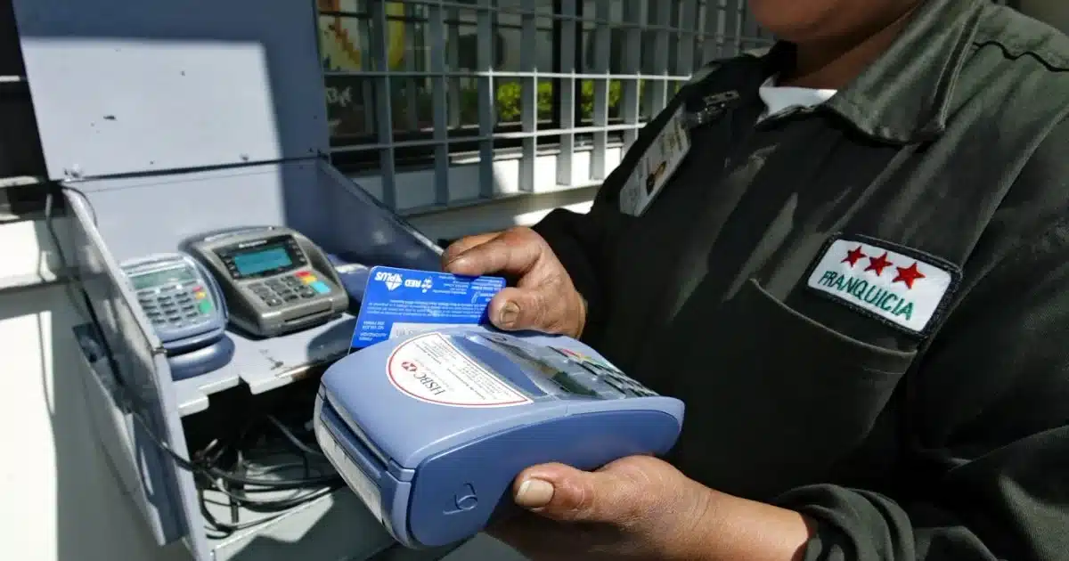 Worker in uniform uses a blue handheld card payment terminal, inserting a card into it.
