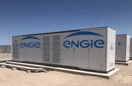 Row of large gray ENGIE industrial generators on concrete pads in a desert under a clear blue sky, ready to supply power.