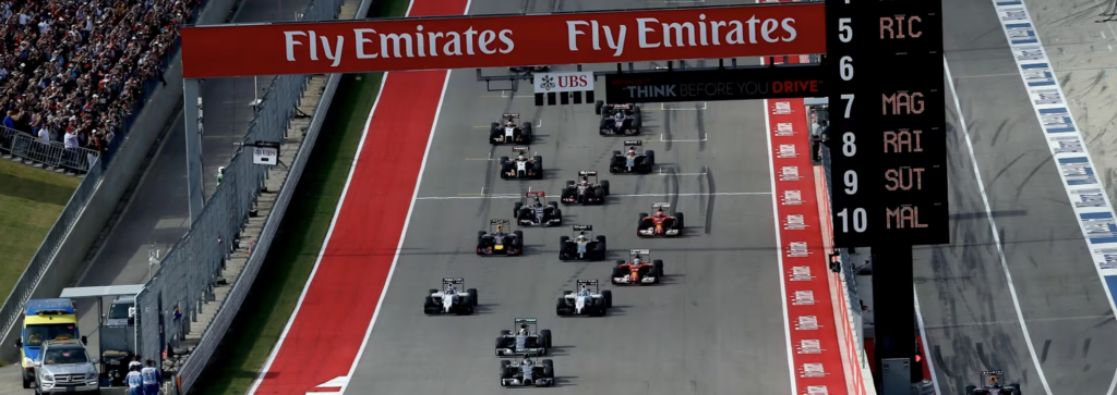 houston f1 - Petróleo y Energía Aerial view of a Formula 1 race start with many cars lined up on the grid under a Fly Emirates banner.